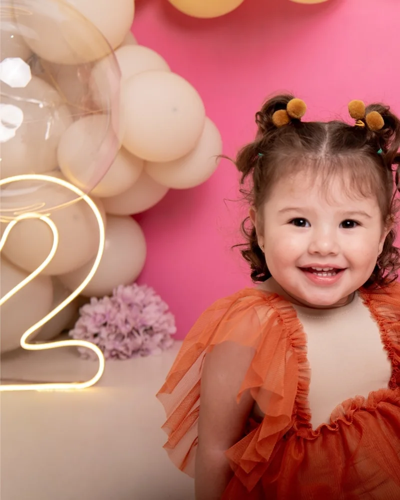 Niña soplando su torta de cumpleaños en el set rosado