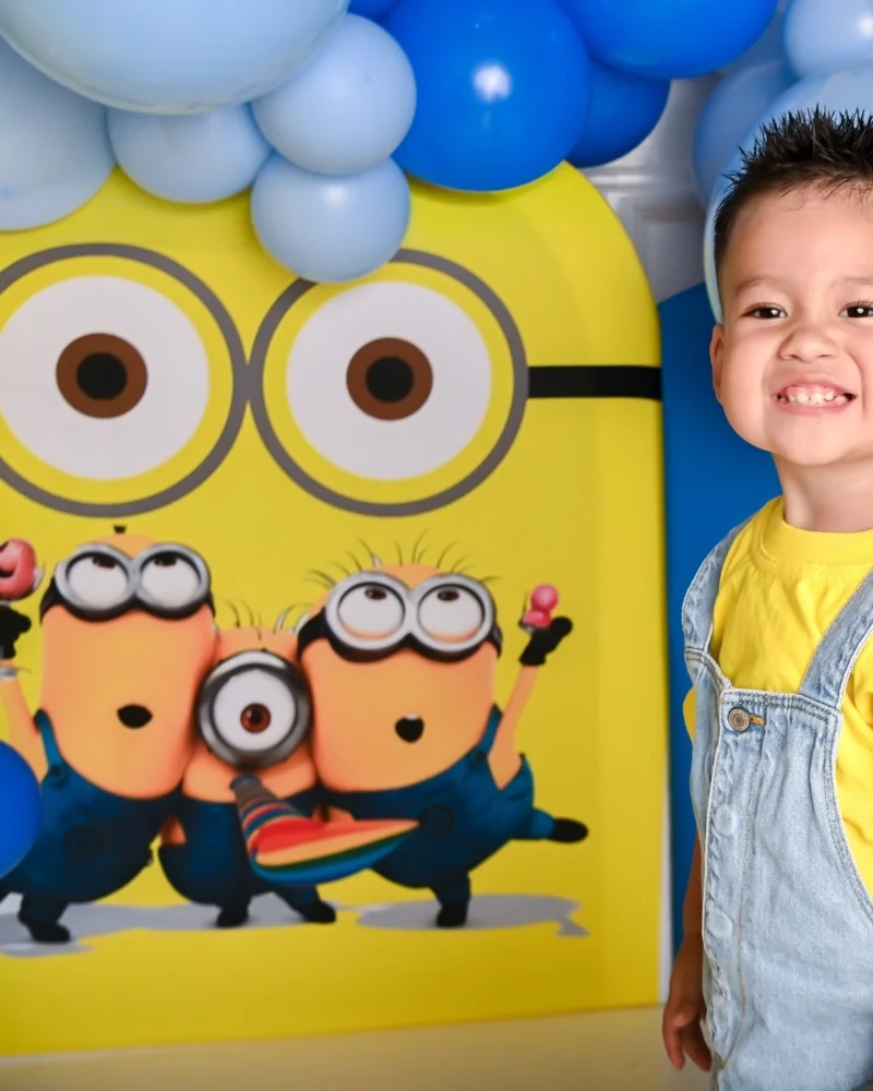 Niño sonriente en un set de Minions con globos azules y amarillos