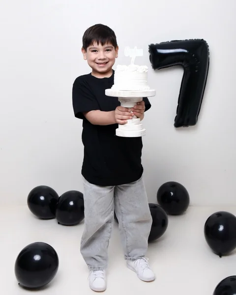 Niño de siete años sentado entre globos negros