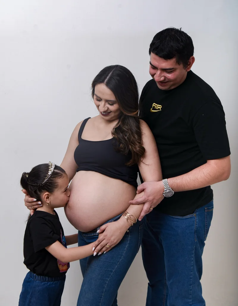 Niña con corona apoyada en la panza decorada de su mamá