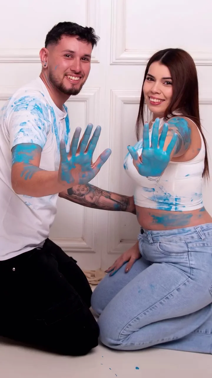 Pareja con las manos pintadas de celeste en su revelación de género